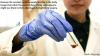 Gloved hand with beaker of gold nanoparticles